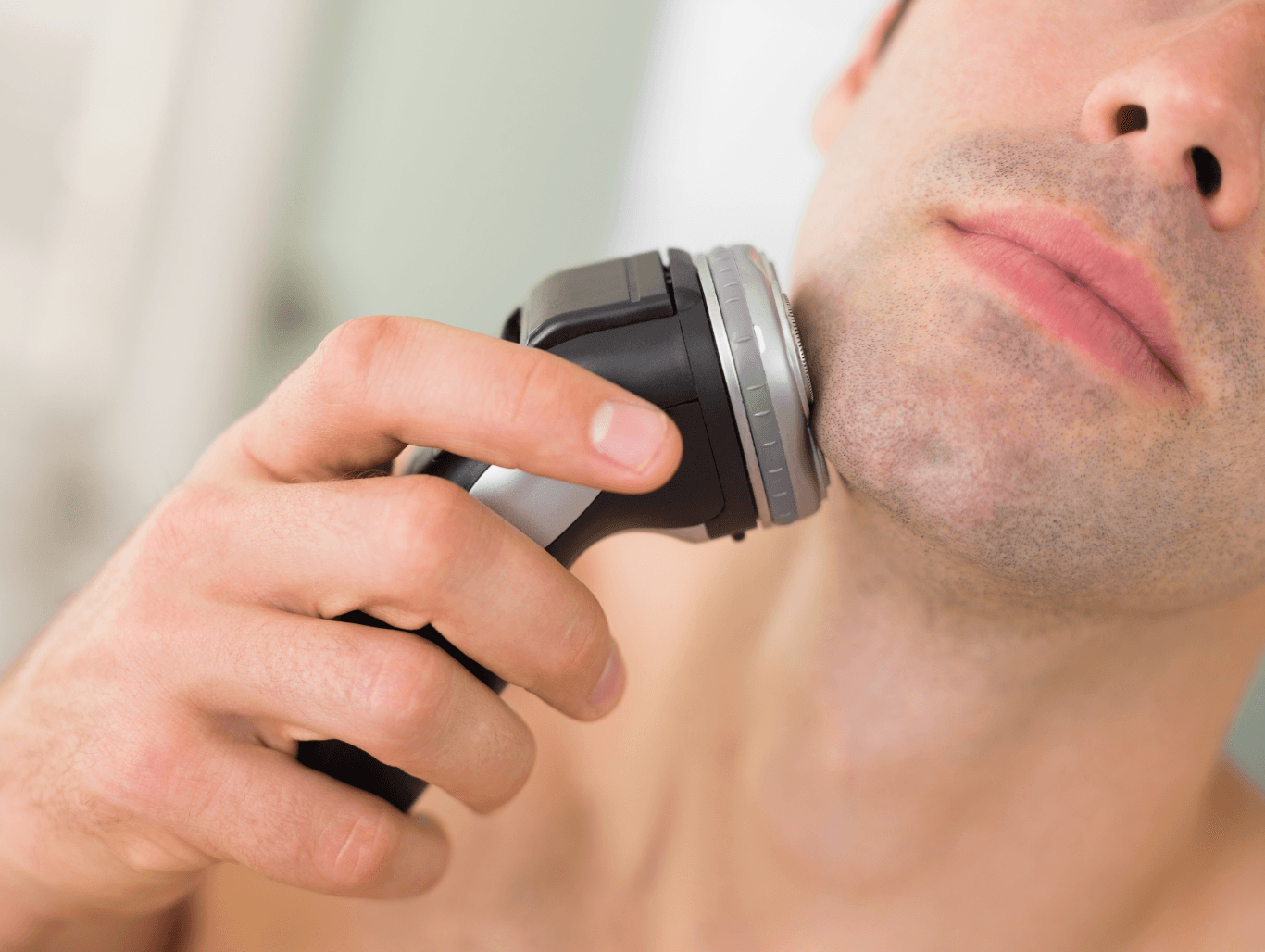 Man using a foil electric shaver on chin after professional facial cleanse at a Weymouth barber