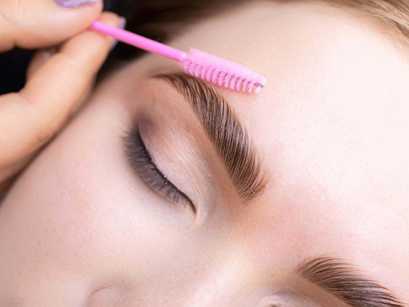 Beauty therapist using a spoolie brush on freshly reshaped eyebrows after waxing treatment in a professional Weymouth salon