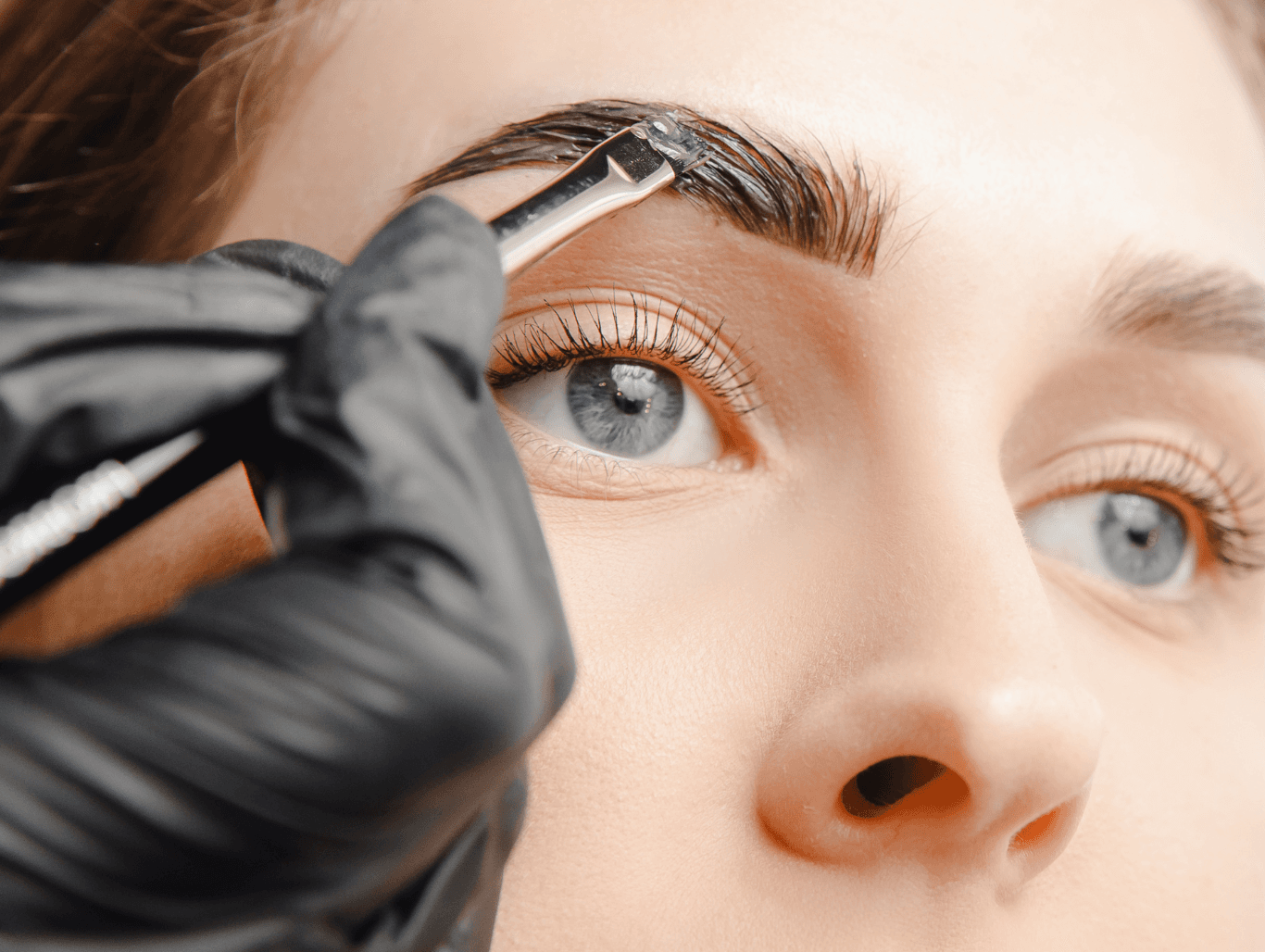 Beauty therapist applying eyebrow tint with precision brush during a brow enhancement service in a Weymouth salon