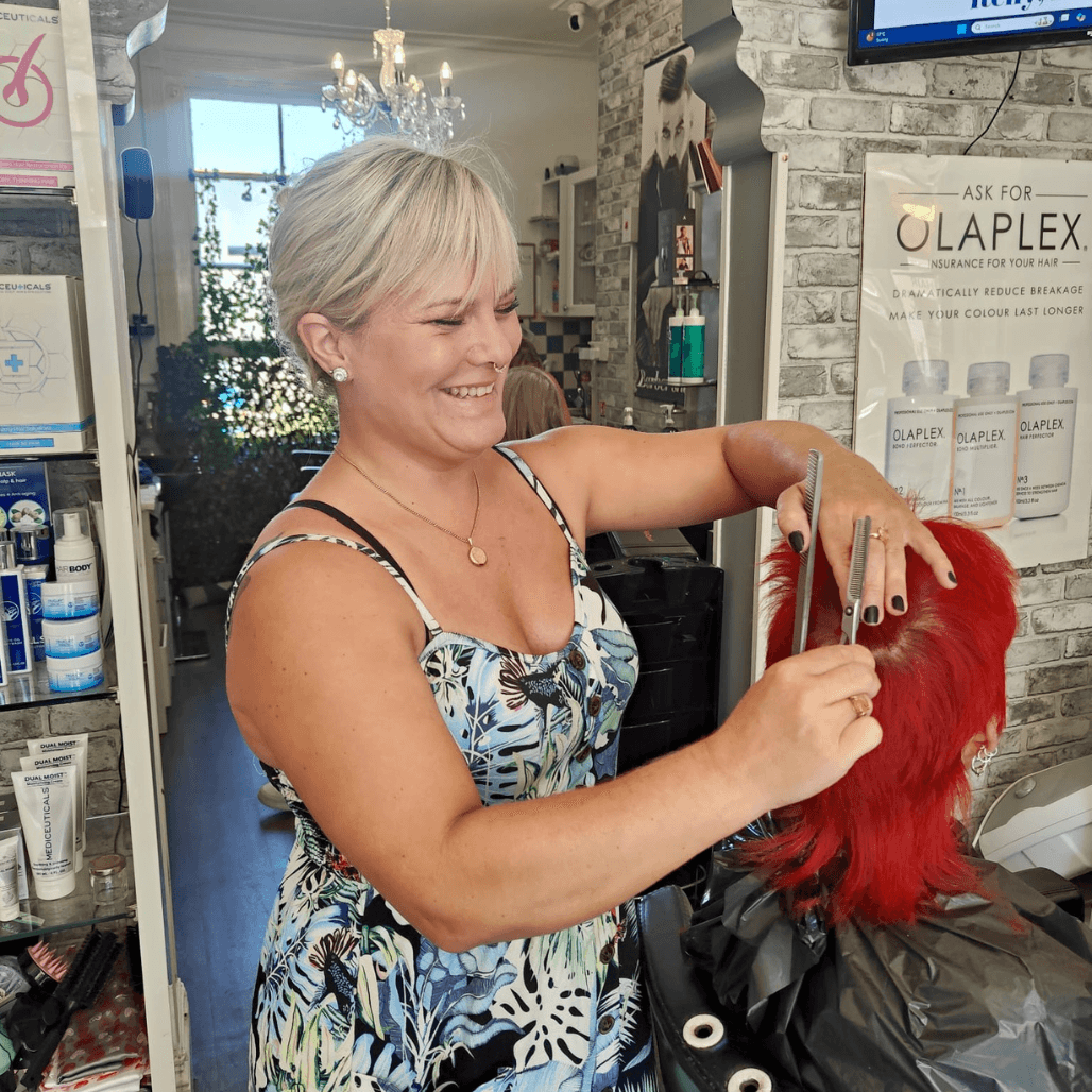 Hannah Tribe, Salon Director at Changing Grooms, smiling with wavy blonde hair and natural makeup look