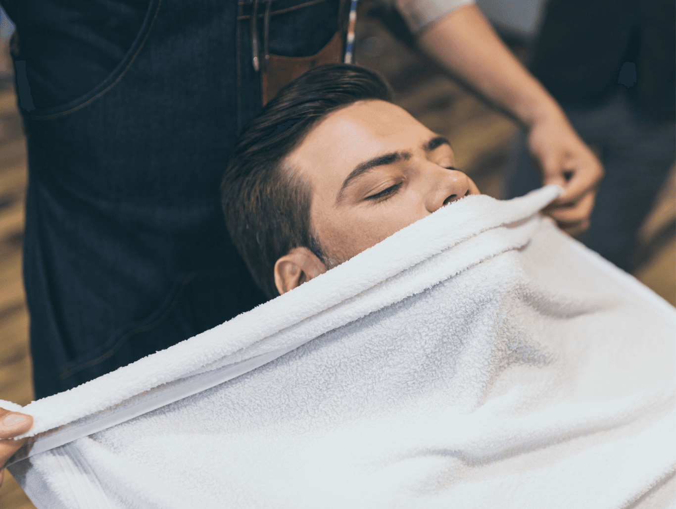 Client receiving a luxury hot towel treatment before a traditional cut-throat shave at a barbershop in Weymouth