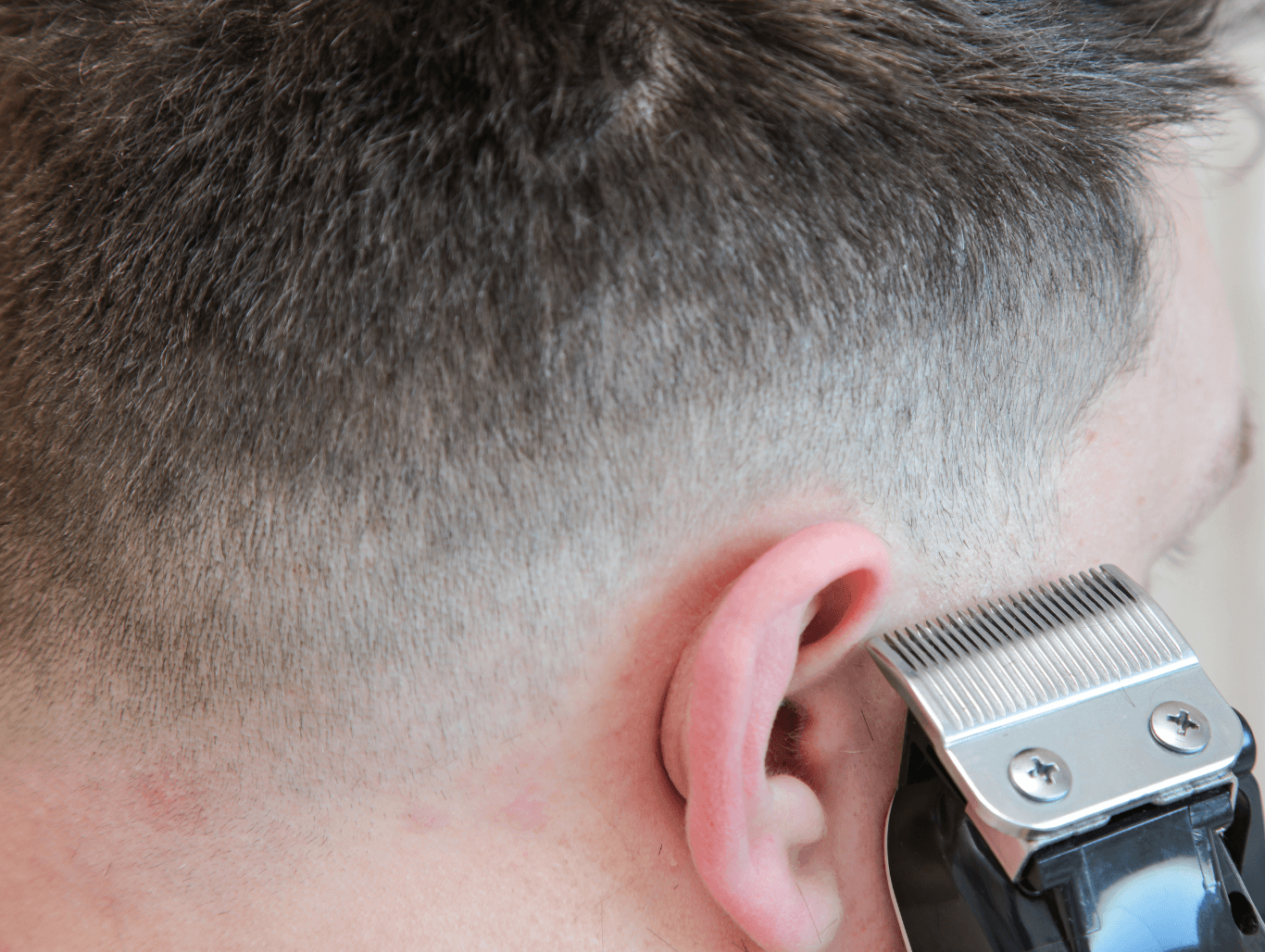 Close-up of clippers blending a low skin fade on short men’s hair at a professional Weymouth barbershop