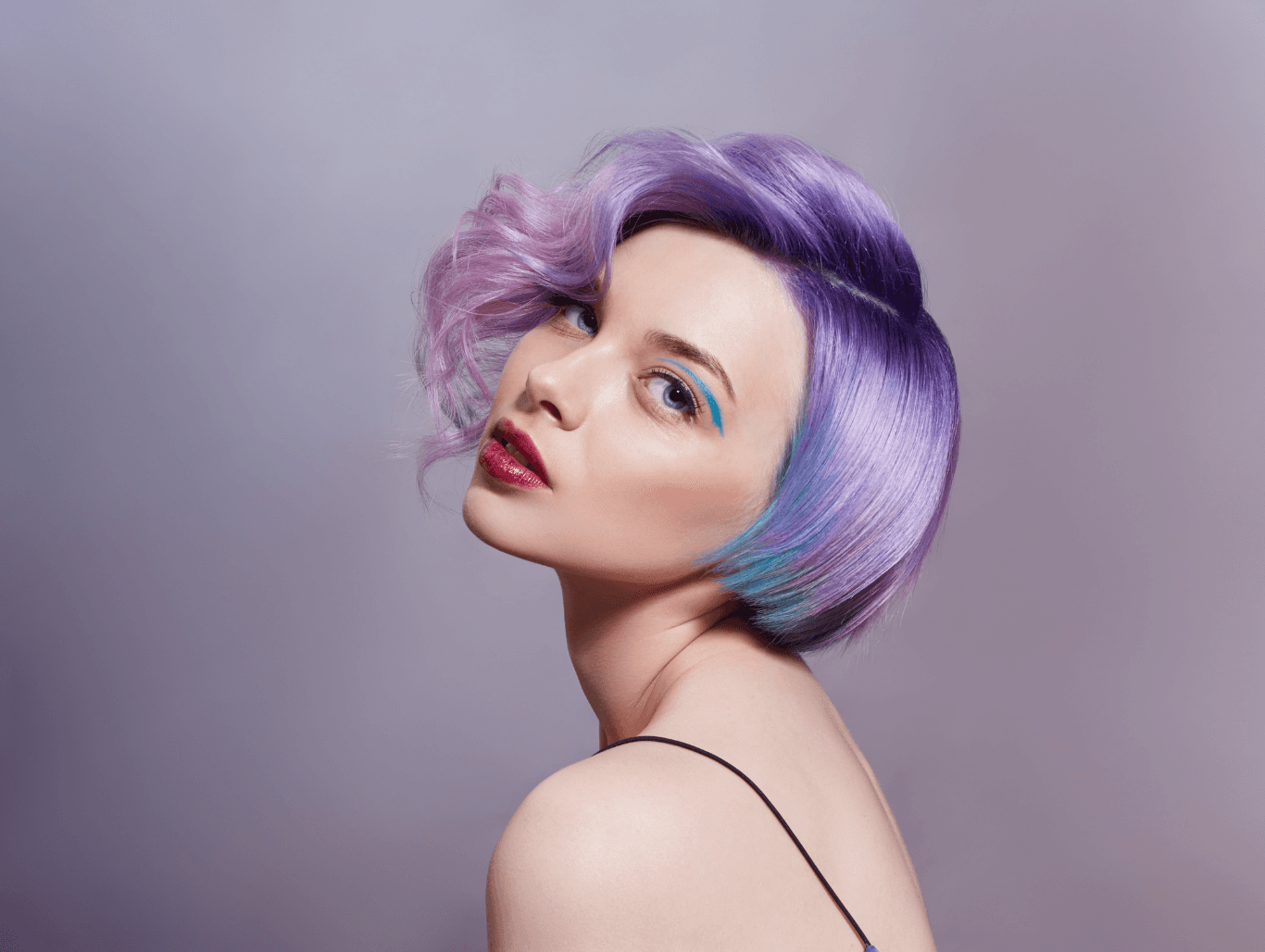 A woman with a short, pastel purple and teal hairstyle, featuring a smooth finish and bold side-swept fringe — a creative and professional colour result by Changing Grooms salon in Weymouth.